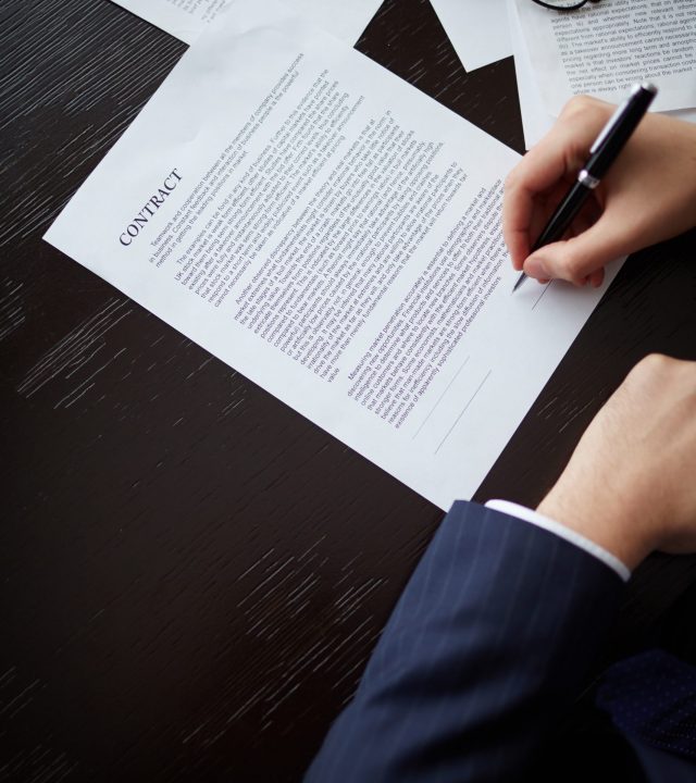 Image of businessman hand with pen signing contract at workplace